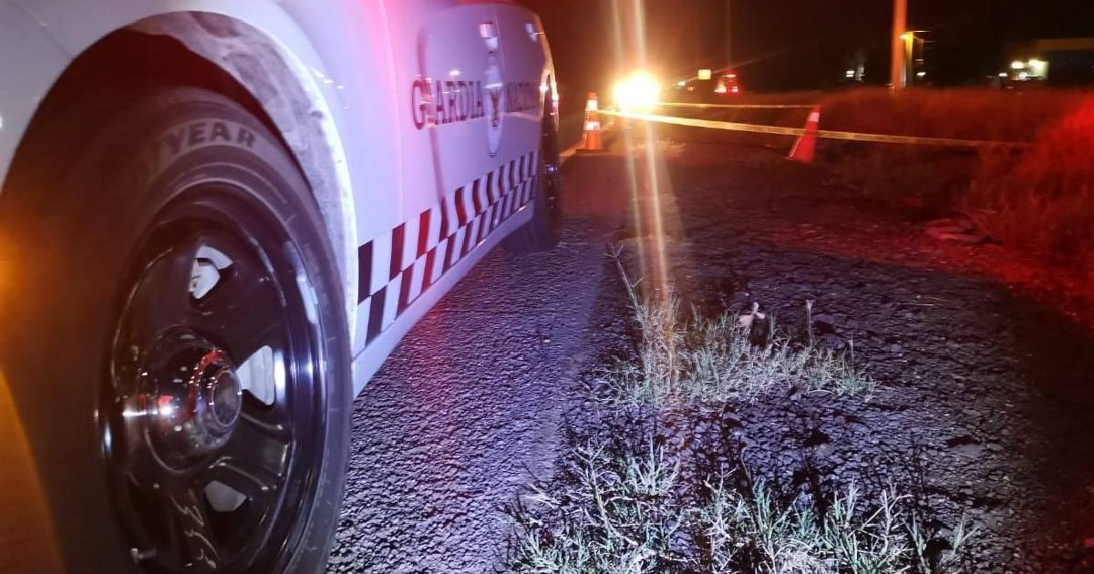 Vehículo de seguridad con luces de emergencia en carretera oscura, rodeado de conos y cinta amarilla.