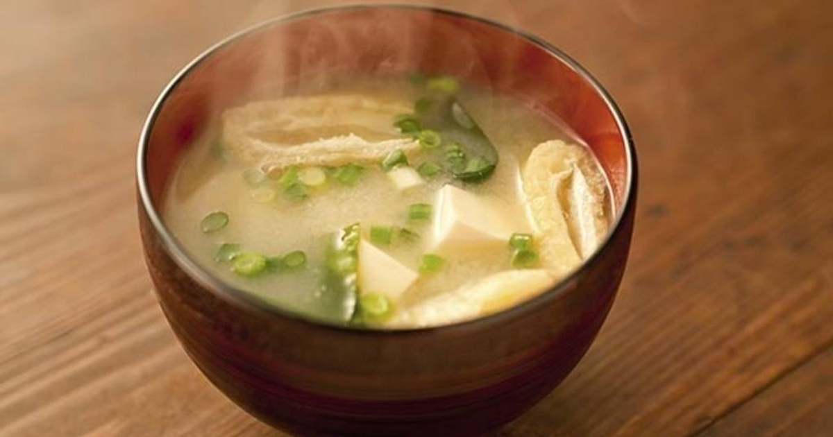 Tazón de sopa miso caliente con tofu y cebolla verde sobre madera