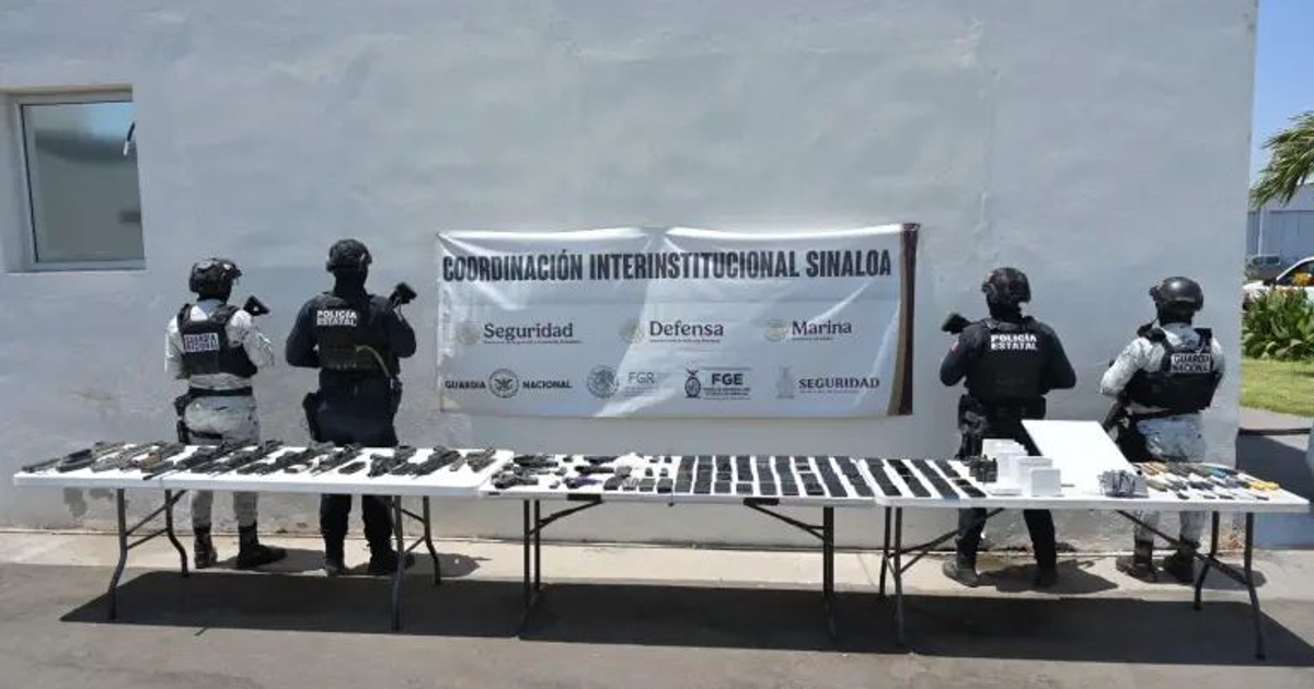 Agentes de seguridad en operativo de inspección penitenciaria en Aguaruto, Culiacán, con armas decomisadas en la mesa.