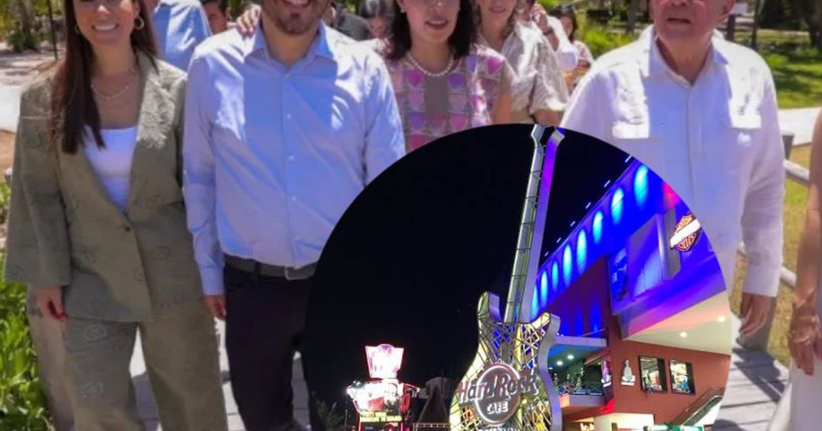 Personas caminando en parque con Hard Rock Café y guitarra luminosa al fondo