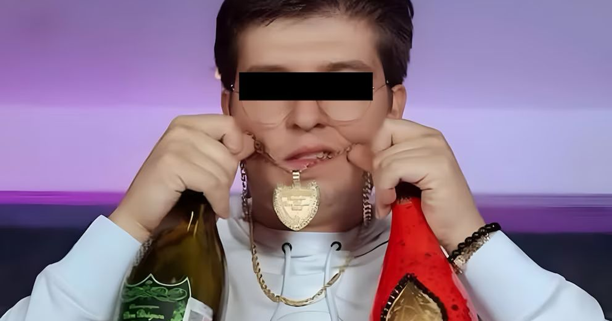 Persona con sudadera blanca sosteniendo botellas y mostrando un collar dorado, fondo púrpura.