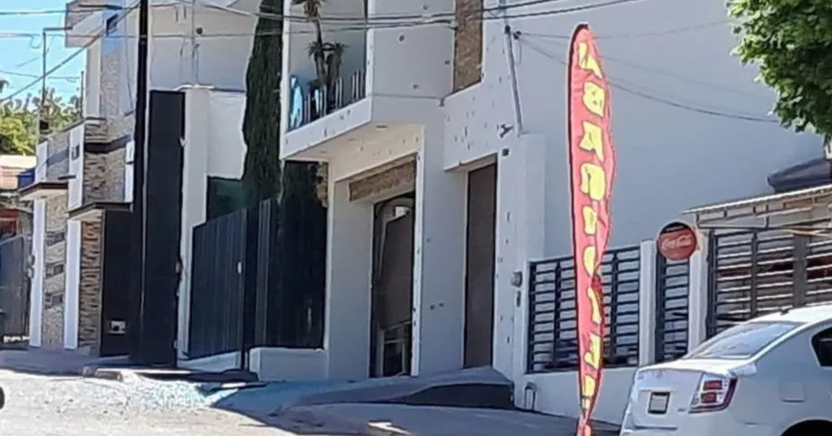 Calle en Lázaro Cárdenas de Culiacán con casas, auto blanco y bandera roja tras tiroteo.