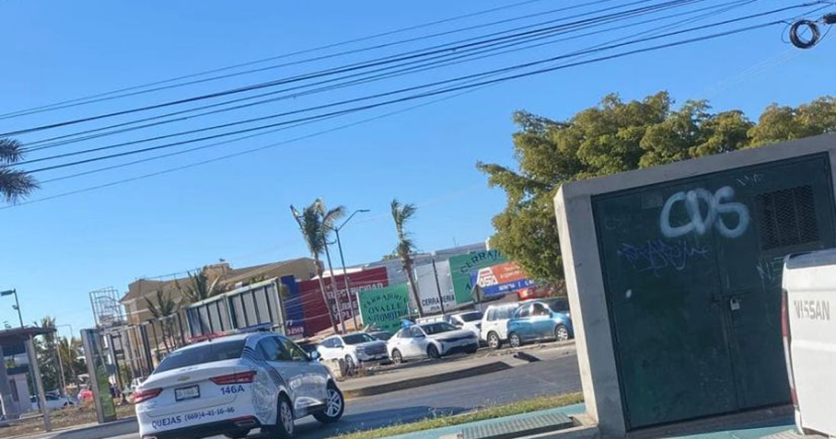 Escena urbana en Mazatlán con autos y edificios tras accidente de tráiler que dañó poste eléctrico.