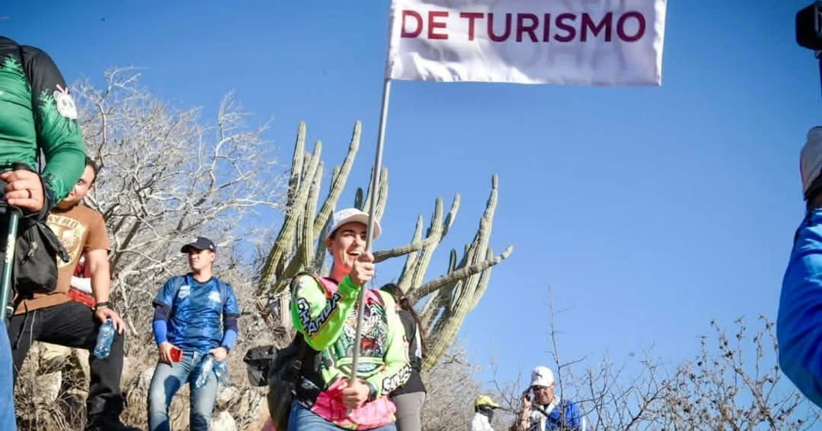Grupo de personas en senderismo en Ahome con bandera de turismo