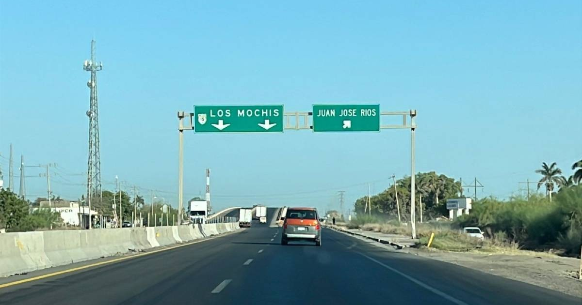 Letrero de tráfico en la Carretera Internacional México 15 con direcciones a Los Mochis y Juan Jose Rios, vehículos en movimiento y cielo despejado.