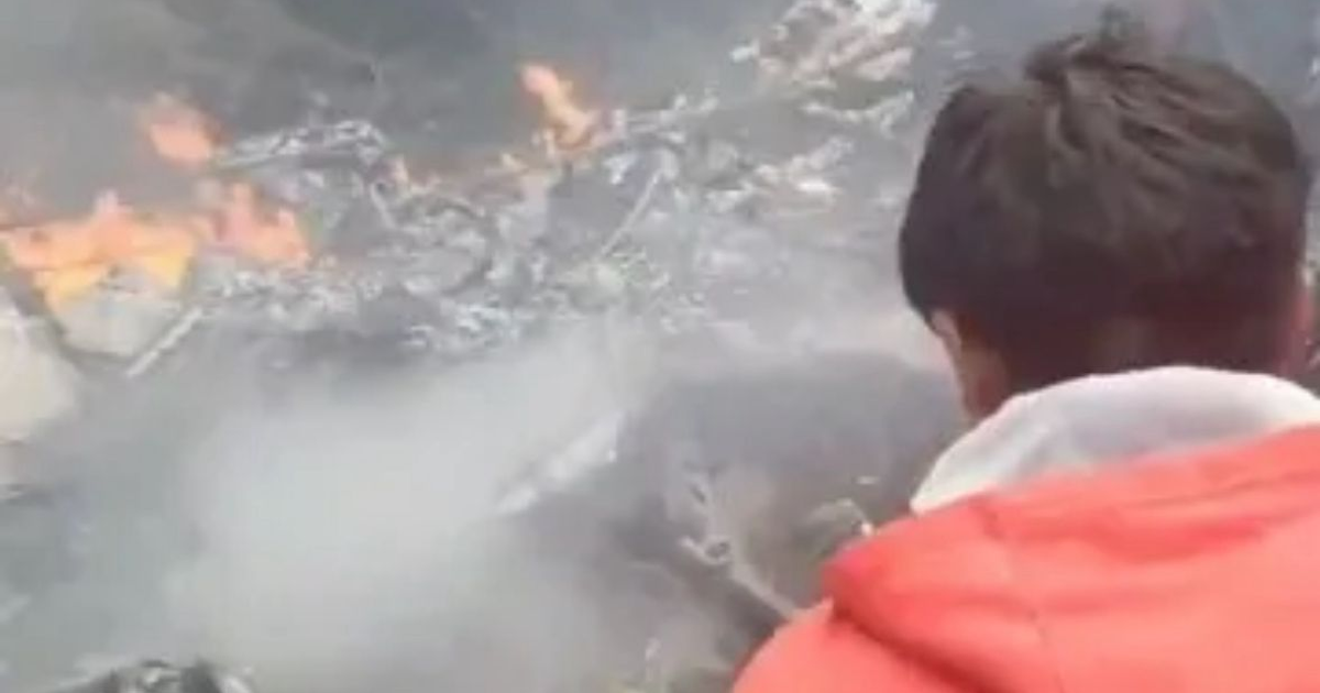 Persona observando incendio y escombros tras accidente de avioneta en Tapachula