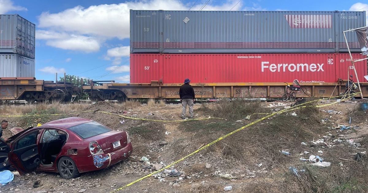 Paisaje industrial con tren de carga y automóvil dañado en Culiacán, relacionado con accidente ferroviario.