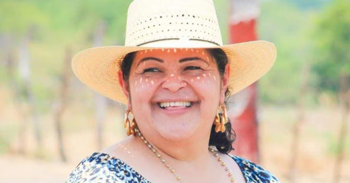 Mujer sonriente con sombrero de paja en un entorno natural