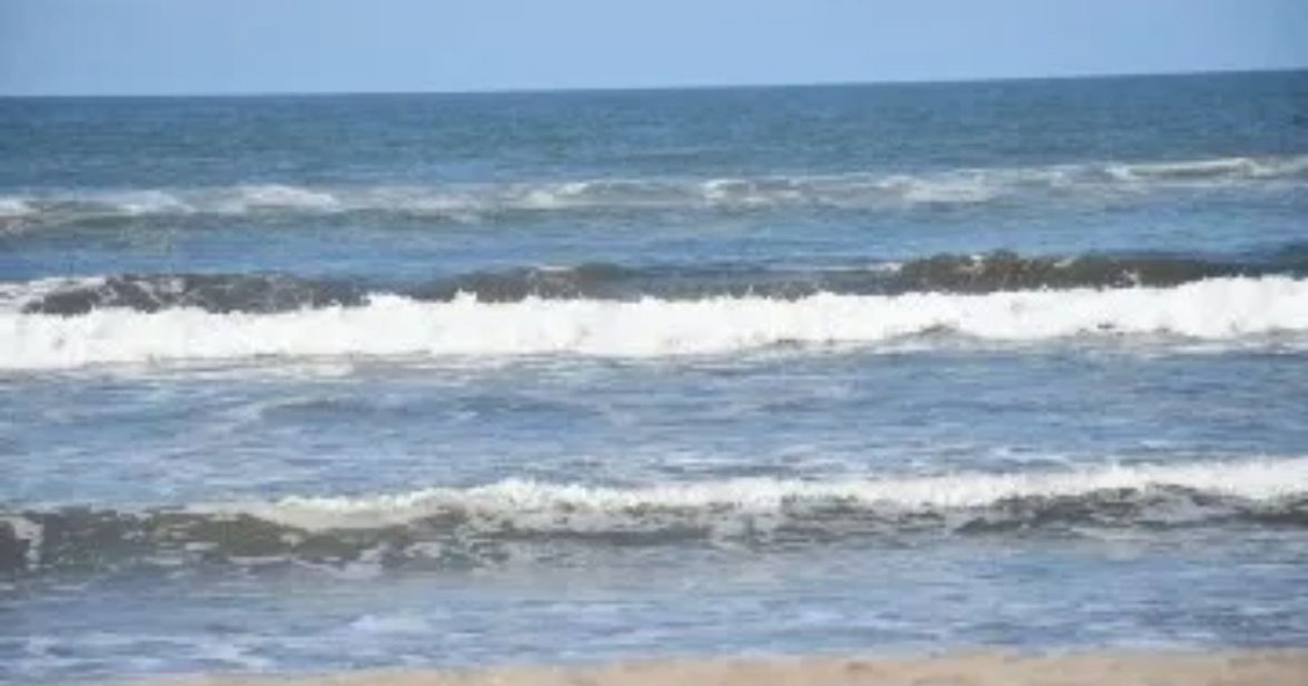 Olas rompiendo en una playa del Pacífico Mexicano durante una alerta de Mar de Fondo, con un cielo despejado y tonos azules en el agua.
