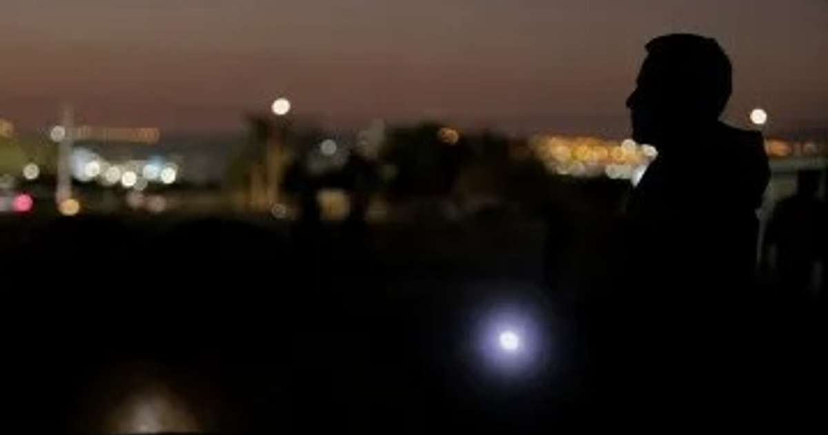 Silueta de una persona en la noche con luces de ciudad de fondo, simbolizando apagones en Mazatlán.