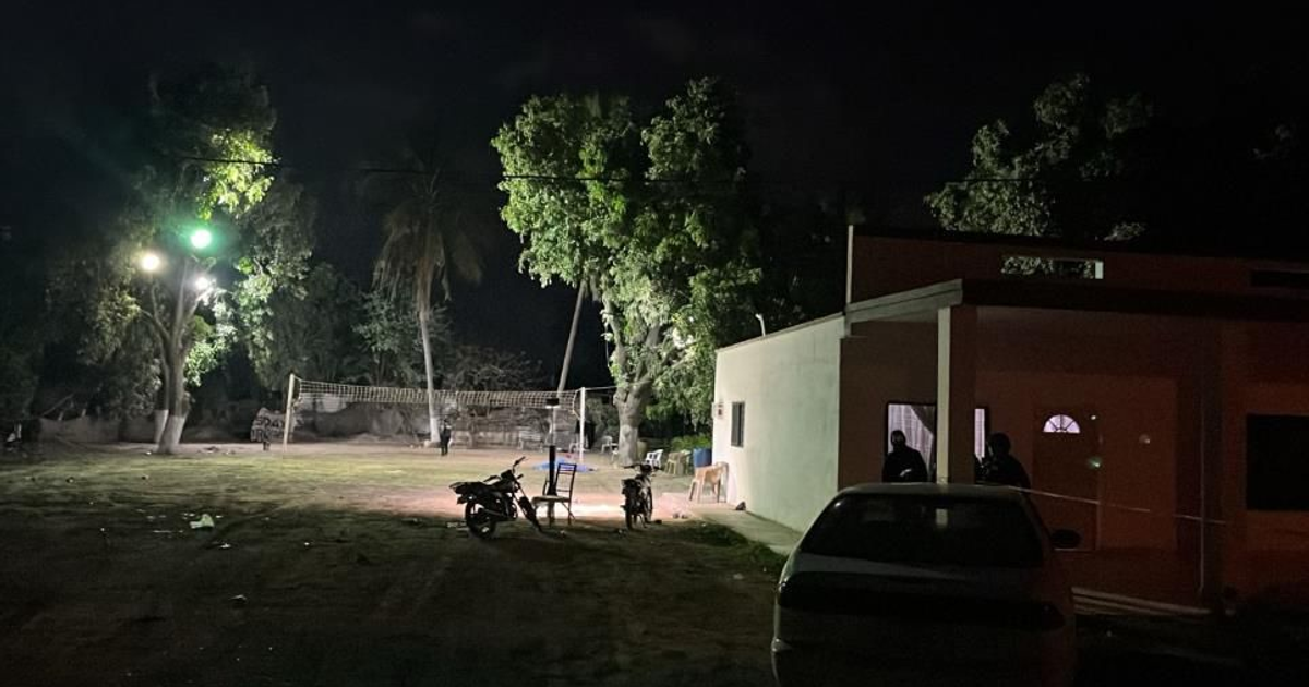 Área exterior nocturna con cancha de voleibol y vehículos estacionados en Navolato