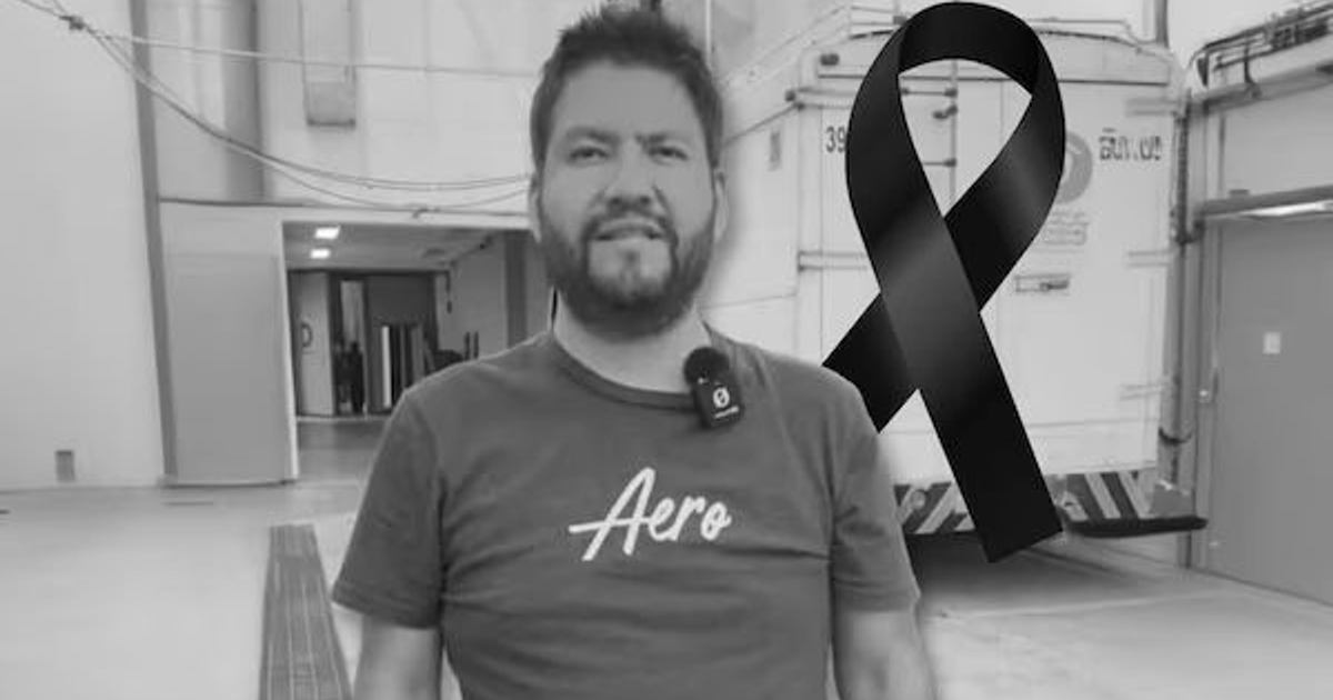 Hombre de pie con camiseta 'Aero' y cinta de luto en espacio cerrado