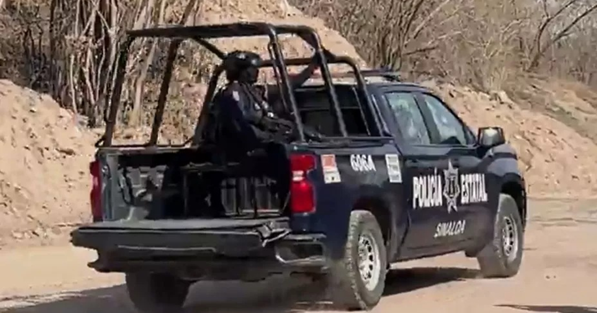 Camioneta de la policía estatal de Sinaloa en un entorno rural desértico, con un oficial armado en la parte trasera.
