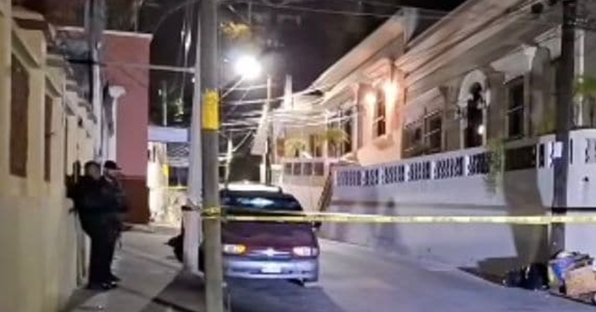 Calle nocturna acordonada en Mazatlán tras un ataque a balazos, con dos personas y un vehículo estacionado.