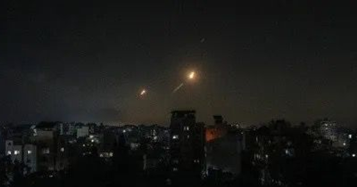 Vista nocturna de Teherán con luces en el cielo durante un ataque militar.