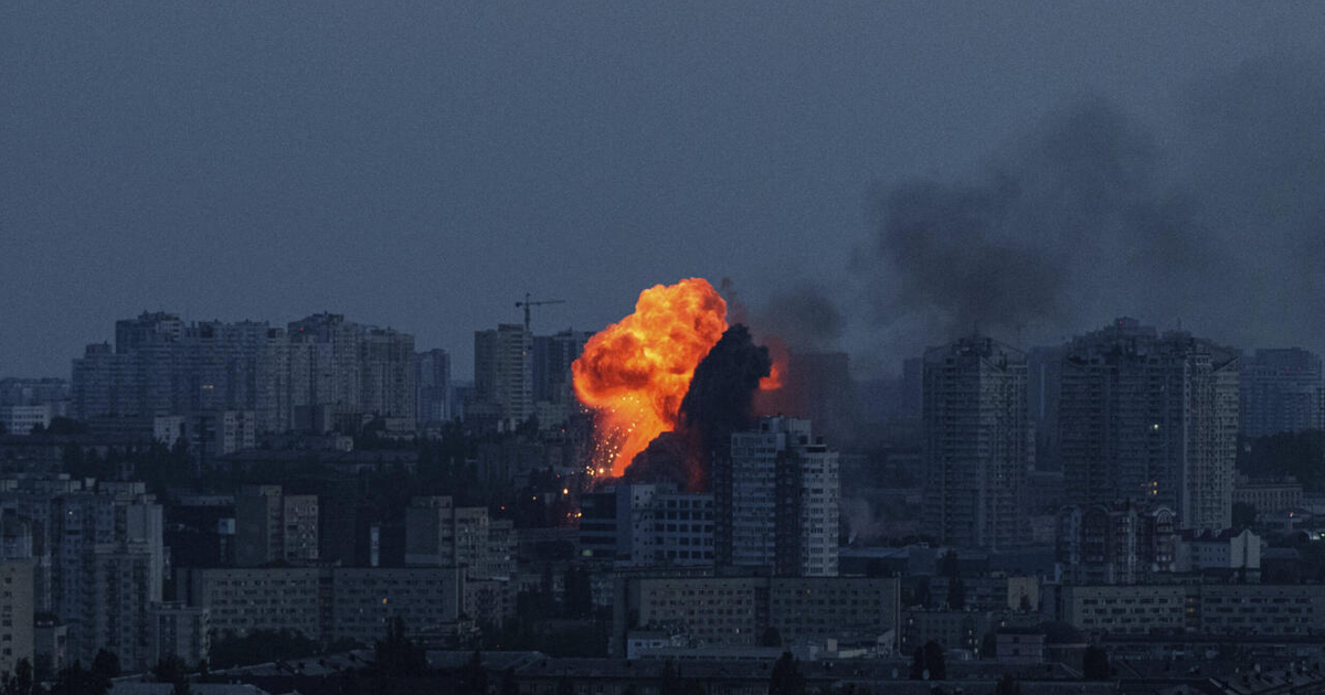 Explosión nocturna en Kiev con llamas y humo entre edificios tras ataque de drones y misiles.