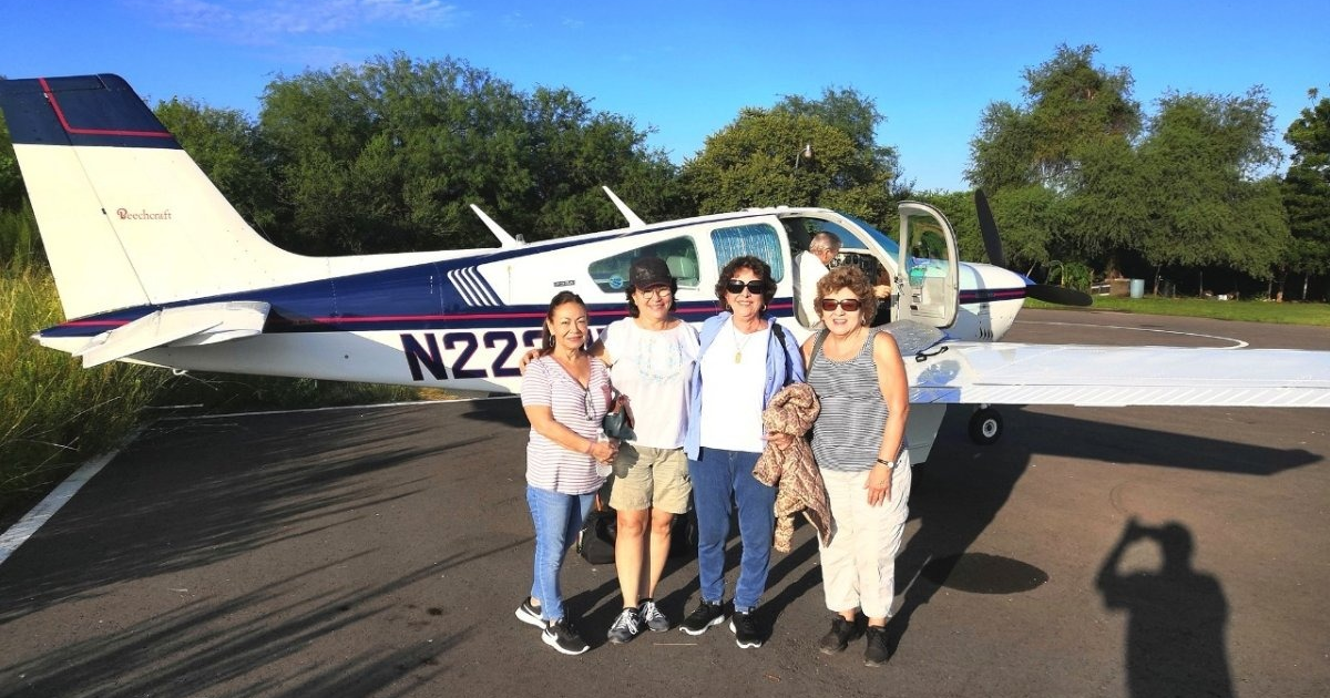 Cinco personas posando frente a un avión pequeño en una pista de despegue, representando la llegada de Flying Doctors of Mercy para atención médica gratuita.