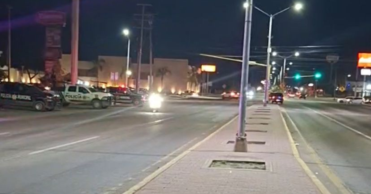 Calle nocturna en Mazatlán con vehículos policiales y tráfico, reflejando un ambiente de tensión tras incidentes violentos.