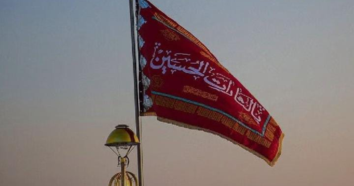 Bandera roja con inscripciones árabes ondeando en la mezquita de Jamkaran, Qom, al amanecer.