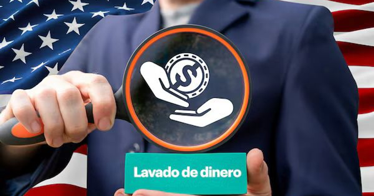 Persona con lupa enfocando símbolo de lavado de dinero sobre fondo de bandera estadounidense