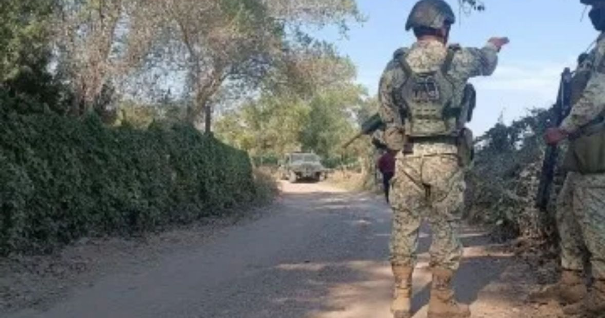 Soldados en camino rural durante operativo de vigilancia, con uno señalando hacia un vehículo en el fondo.