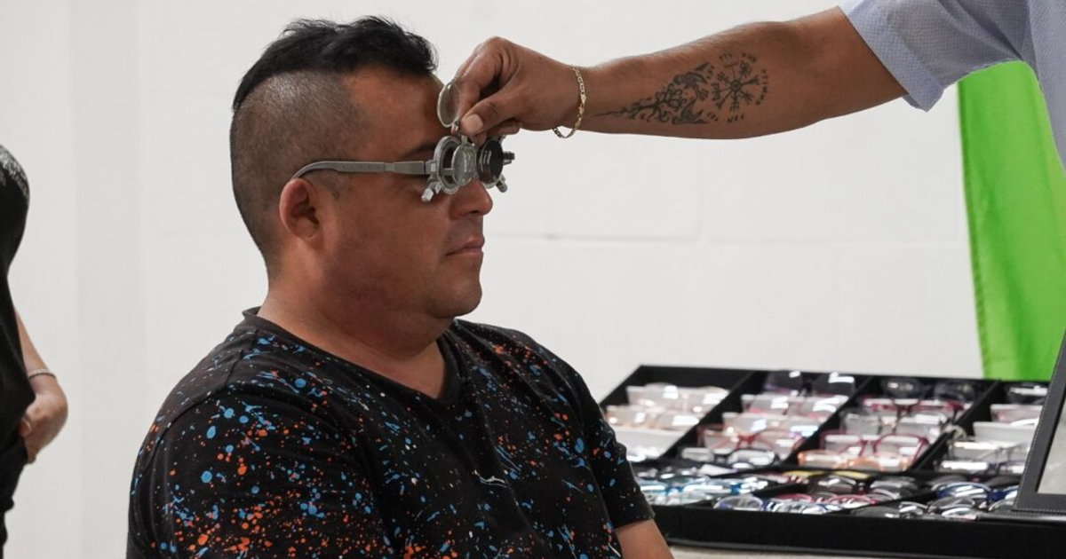 Hombre en examen visual con lentes de prueba durante campaña de salud