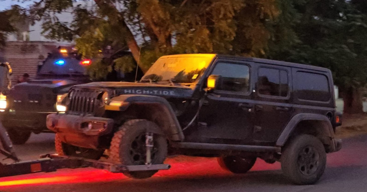 SUV tipo Jeep detenido en carretera durante operativo en Culiacán, con placa 'HIGH TIDE' y vehículos de emergencia al fondo.