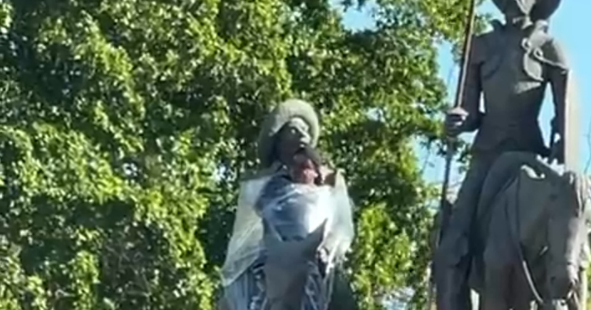 Estatua envuelta en plástico en el Monumento Quijote de la Mancha, con un jinete a caballo a la derecha.