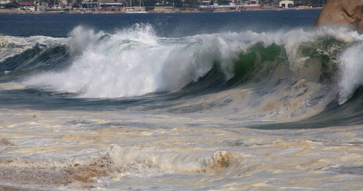 Olas grandes rompiendo en la costa de Sinaloa con espuma blanca y un fondo acuático.