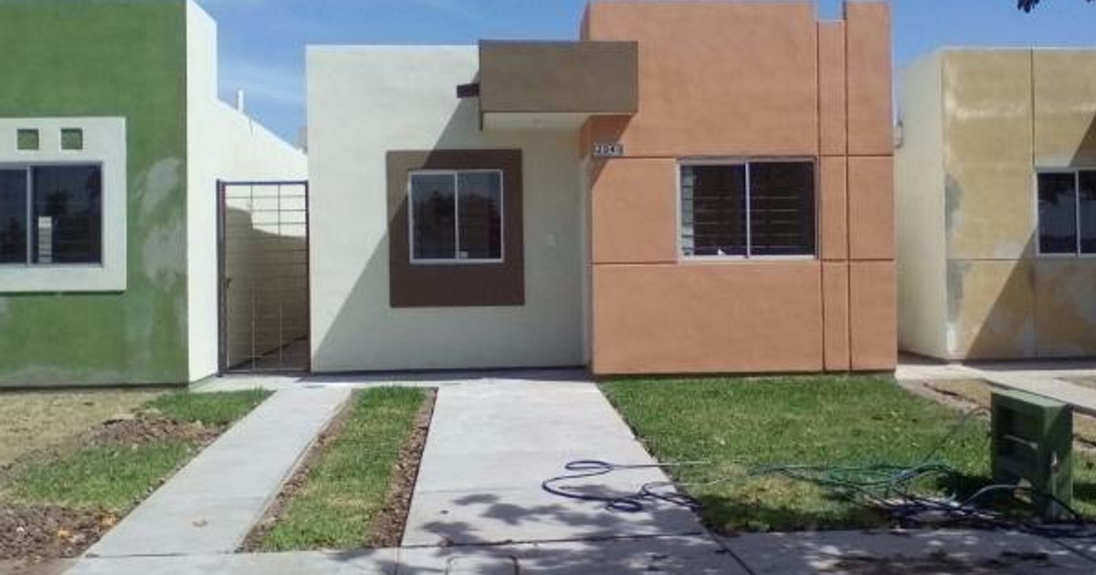 Tres casas de colores con camino de concreto y césped en un día soleado