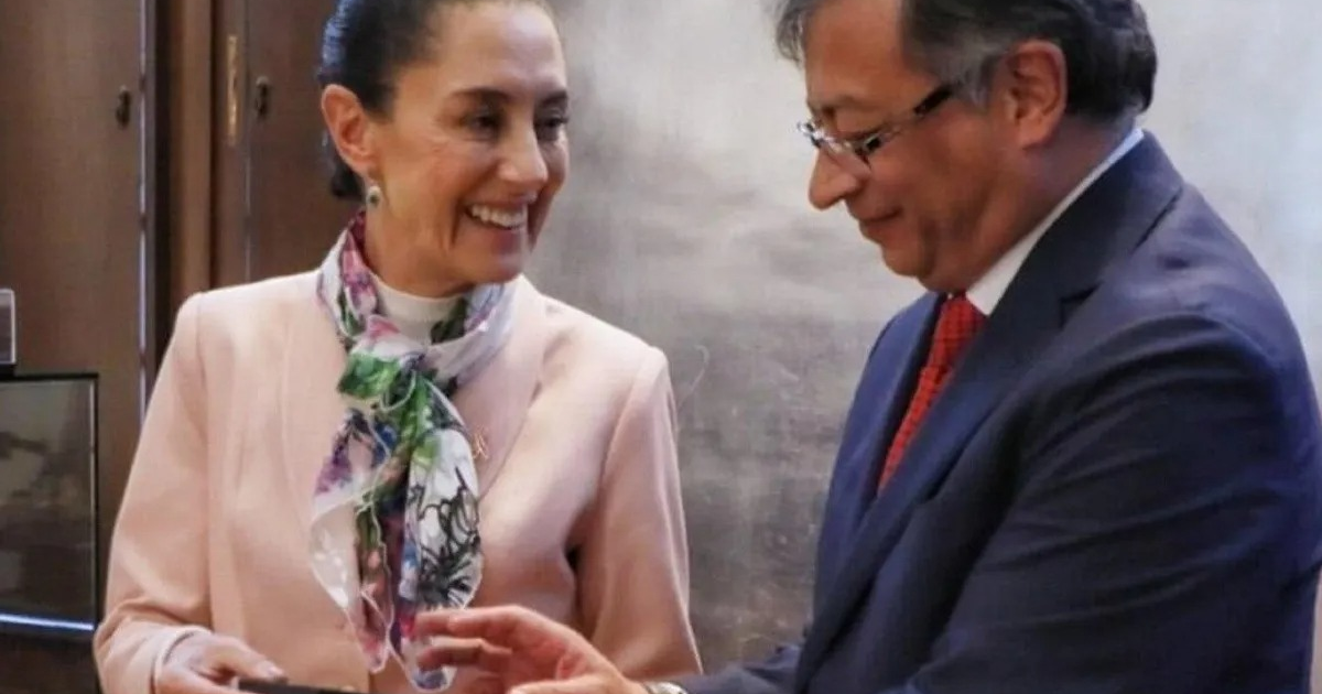 Dos personas interactuando en un entorno formal, una sonríe sosteniendo un objeto mientras la otra observa.