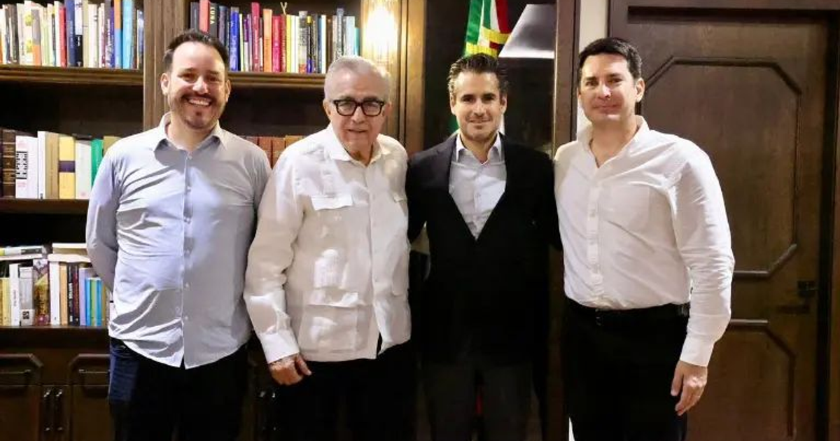 Cuatro personas sonrientes posando frente a una estantería de libros en un entorno profesional.