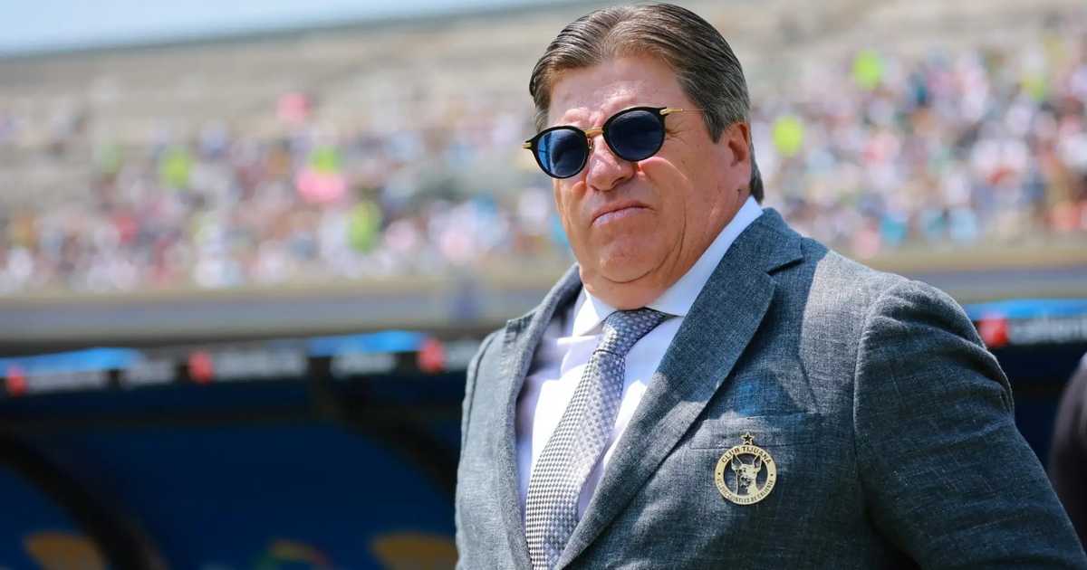 Hombre con gafas de sol y traje gris en evento deportivo al aire libre