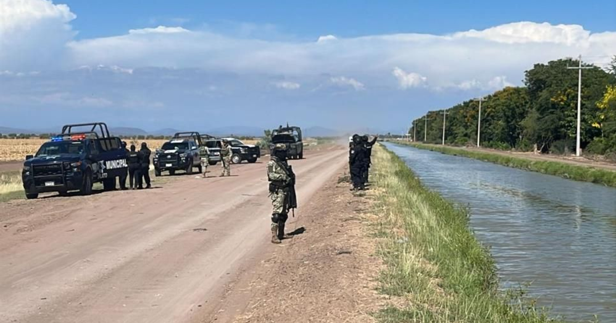 Operativo de seguridad en carretera rural con vehículos y personal uniformado tras hallazgo de cadáver.