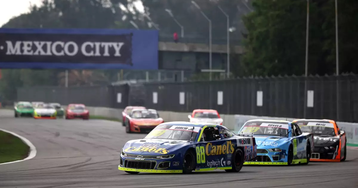Carrera de autos en el Autódromo Hermanos Rodríguez, Ciudad de México, con autos de colores brillantes y patrocinadores visibles.