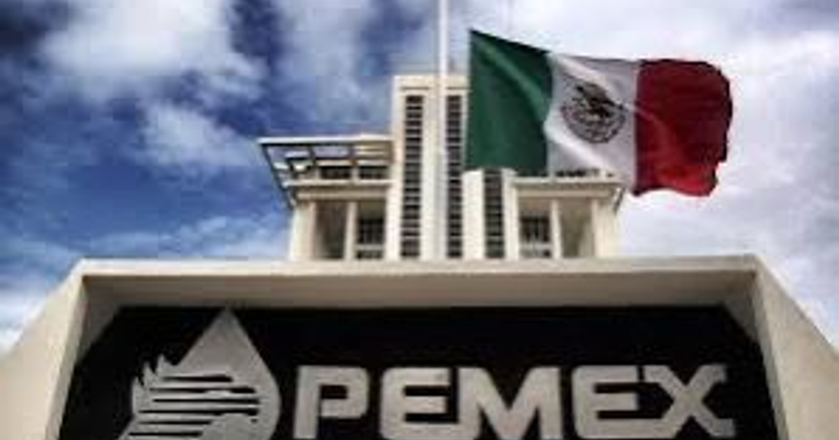 Edificio de Pemex con bandera de México ondeando y logotipo visible, bajo un cielo nublado.
