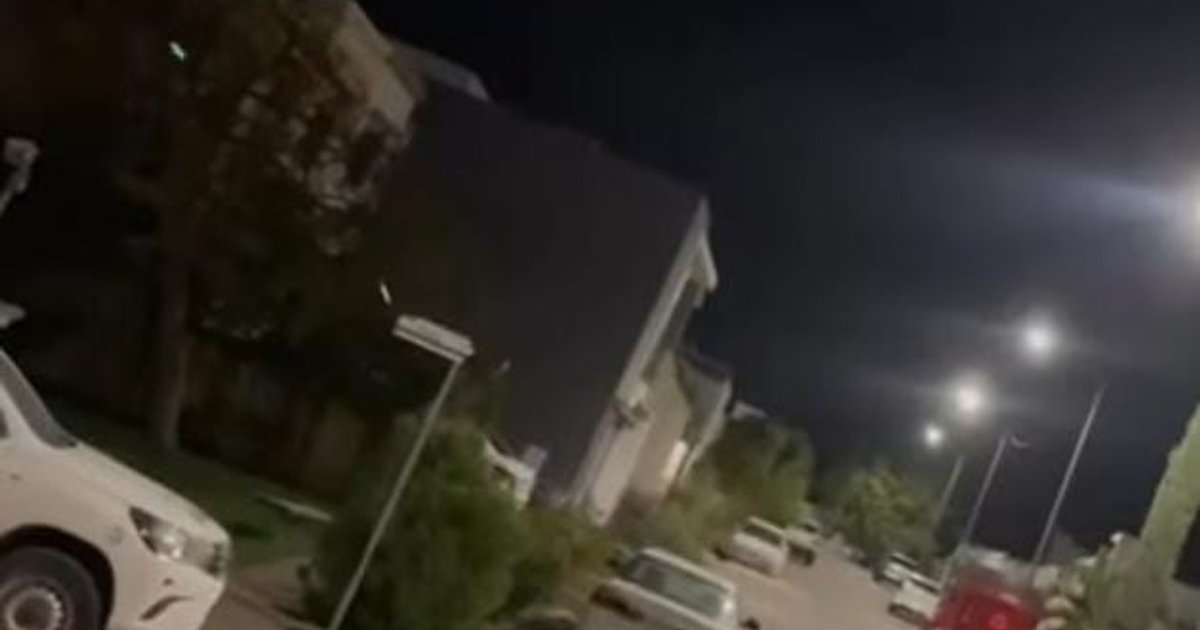 Calle urbana nocturna en Culiacán con luces encendidas y automóviles estacionados, en el contexto de un tiroteo reciente.