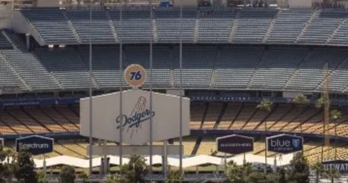 Estadio de béisbol vacío con cartel de Dodgers y anuncio '76'.