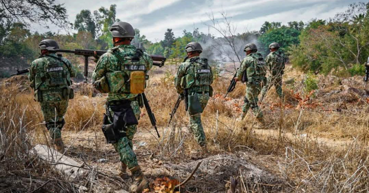 Soldados en uniforme de camuflaje patrullando terreno árido en la sierra de Tepuche, con humo en el fondo.