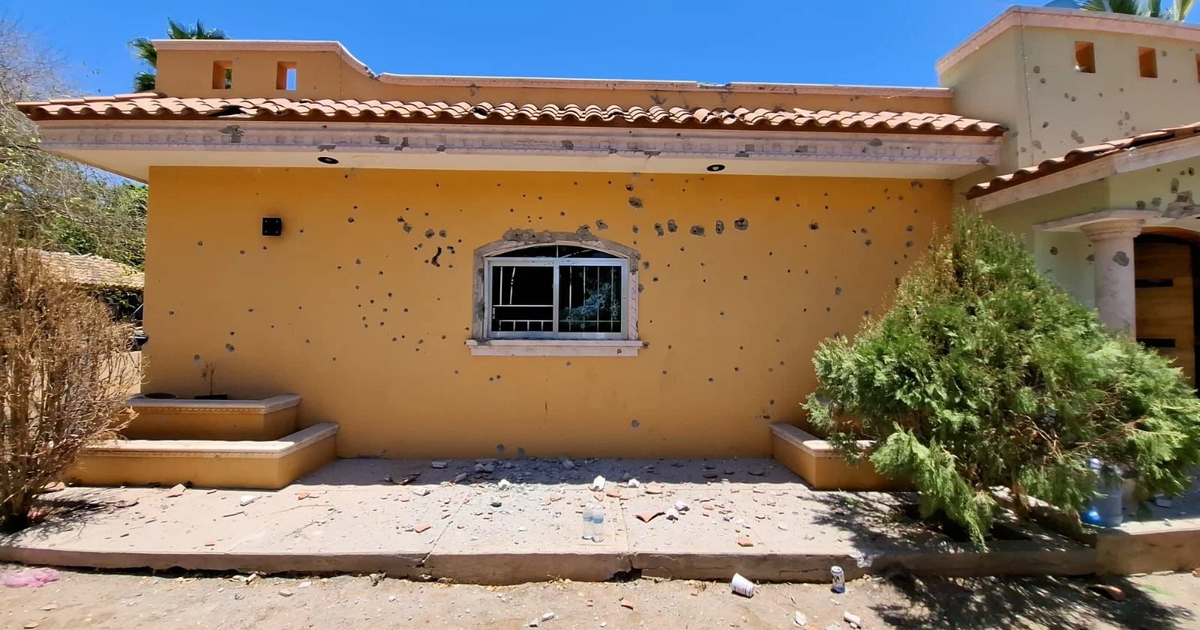 Casa amarilla con agujeros de bala y escombros en Imala, Culiacán.