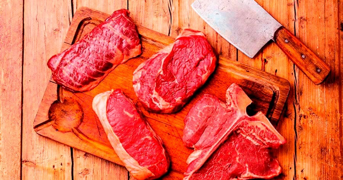 Cortes de carne roja en tabla de madera con cuchillo