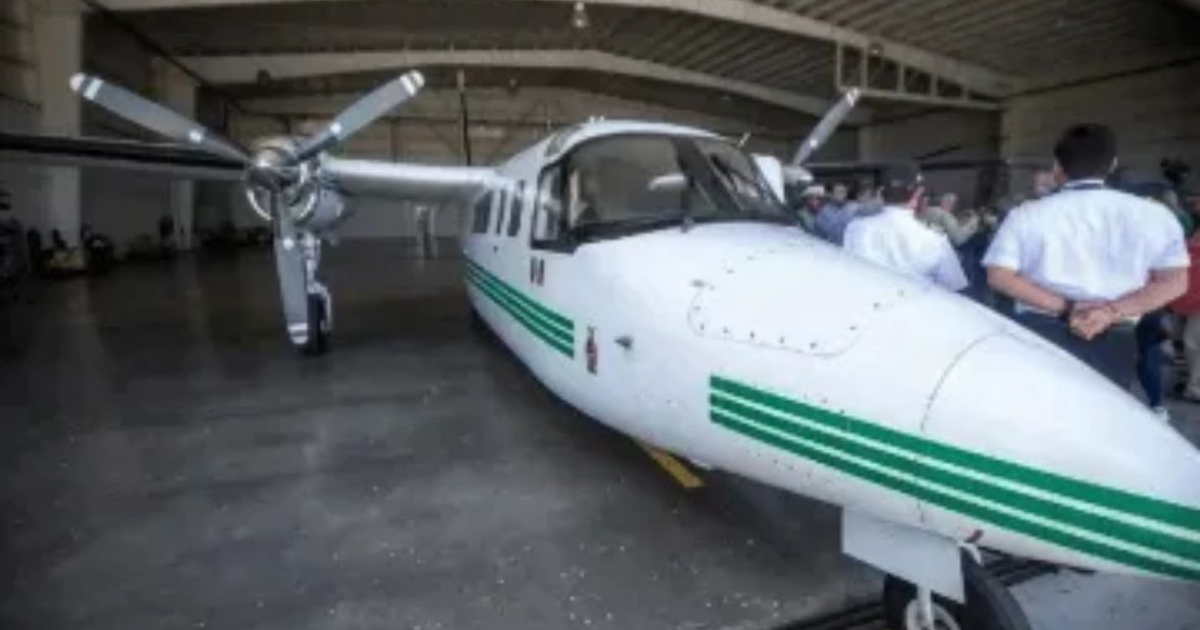 Avión de siembra de nubes en hangar con personal de aviación