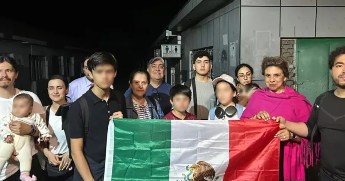 Grupo de mexicanos con bandera de México en evacuación diplomática nocturna en Medio Oriente.