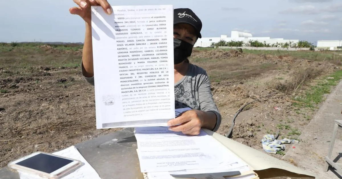 Mujer sosteniendo documento en terreno desértico, simbolizando fraude en venta de terrenos.