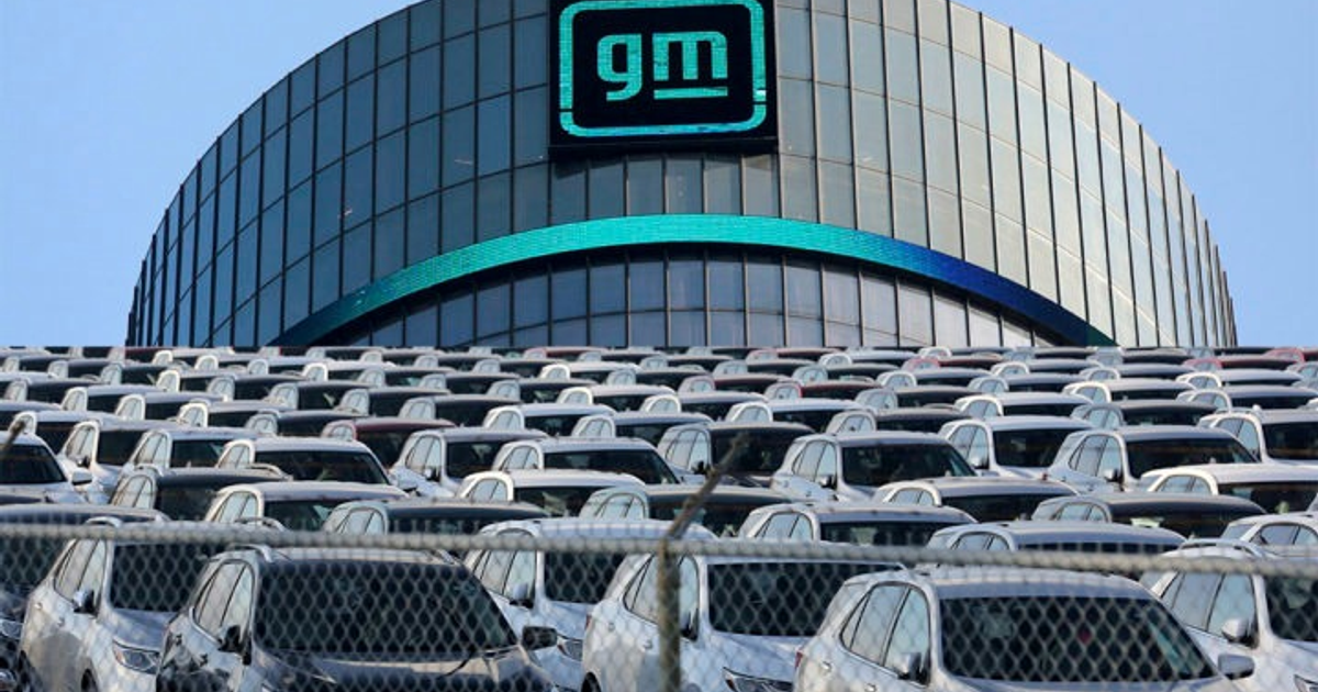 Vehículos estacionados frente a edificio de General Motors, simbolizando expansión manufacturera en EE.UU.