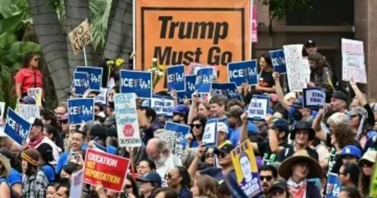 Multitud en manifestación en Los Ángeles con carteles de protesta contra Trump y políticas migratorias.