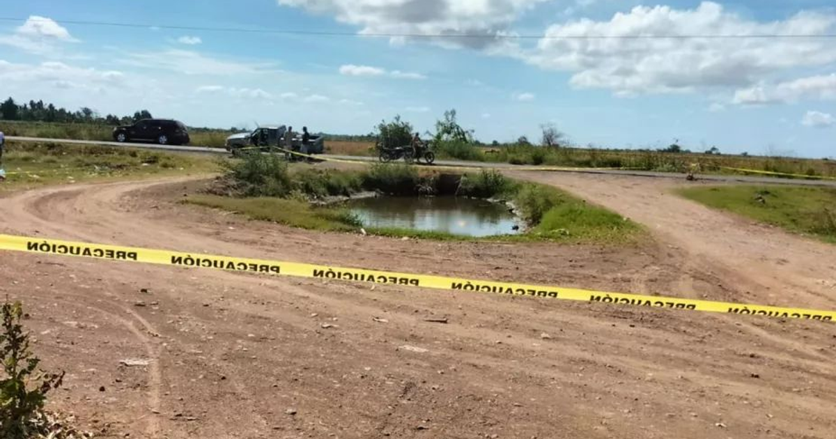 Camino de tierra con estanque y cinta de advertencia en escena de precaución en Tamazula.
