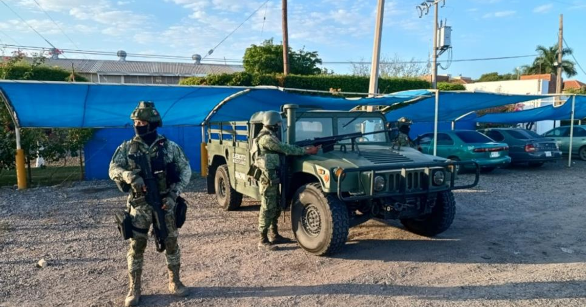 Soldados armados en zona de seguridad con humvee y estructura cubierta con lona azul en Sinaloa.