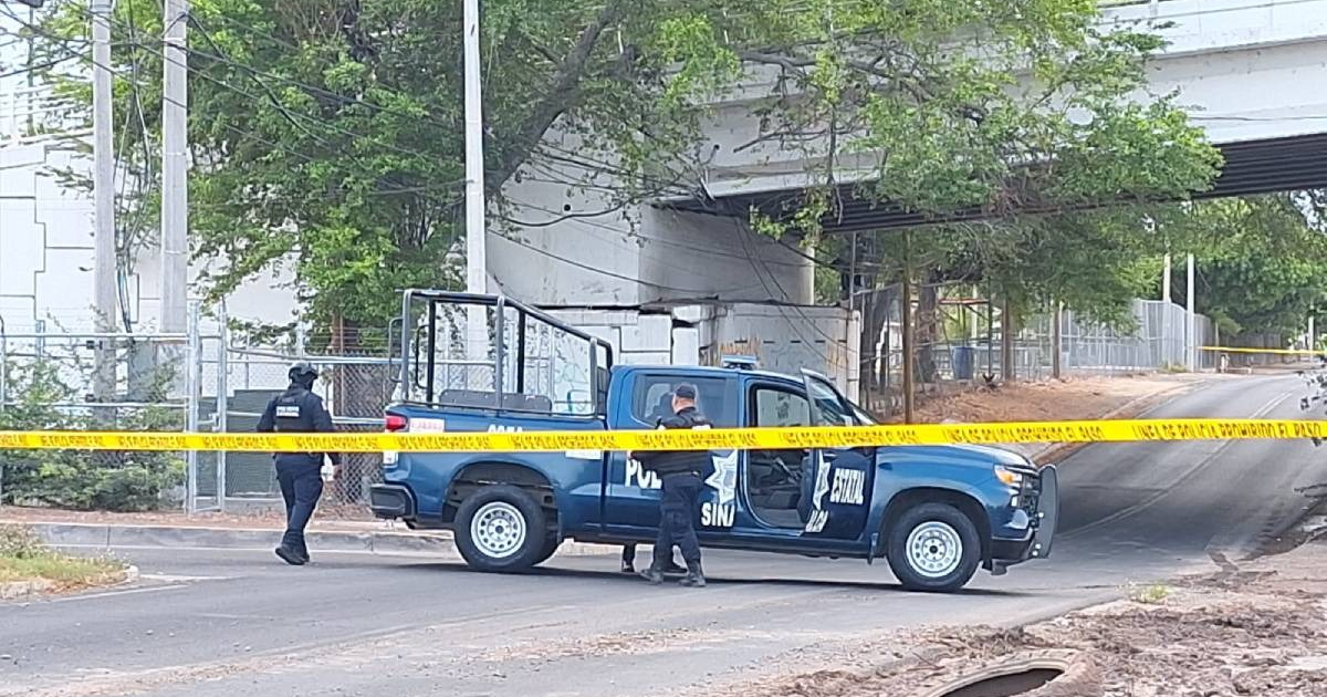 Vehículo policial y agentes en escena del crimen en Culiacán, con cinta amarilla de delimitación.
