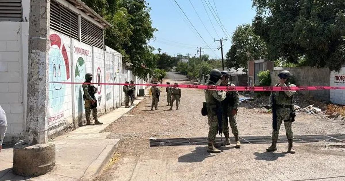 Militares y policías resguardan una escena del crimen en Culiacán, con cinta de advertencia y murales al fondo.